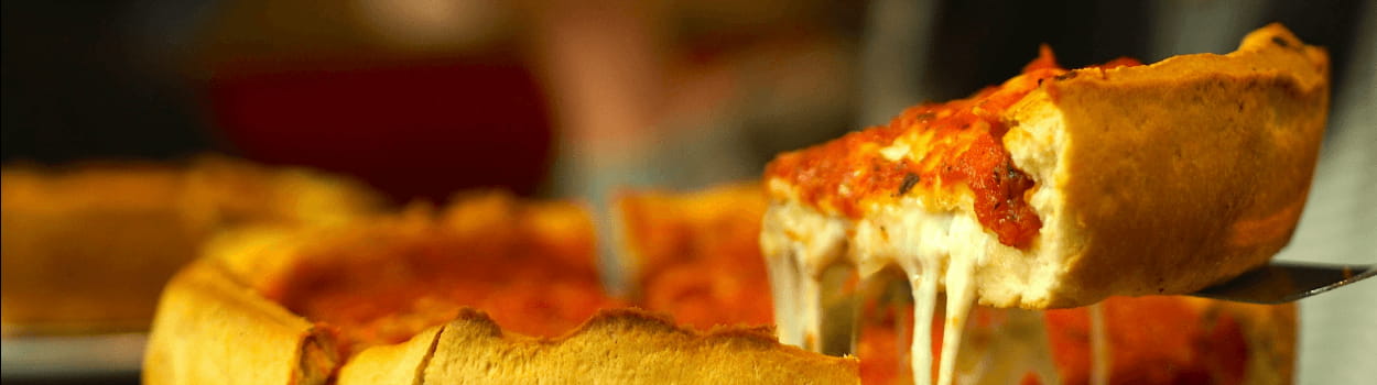 A Chicago deep-dish pizza with one slice being lifted up by a pizza cutter.