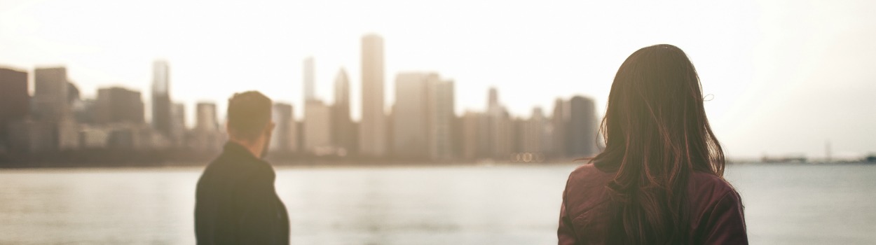 A man and woman look out at the water with the skyline in the background at Milton Lee Olive Park, Chicago.