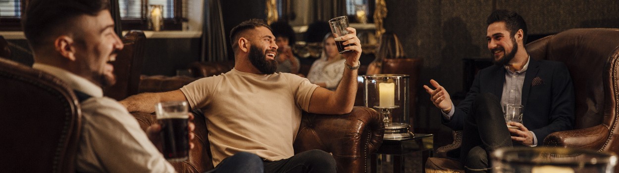 A group of men in a lounge having a conversation and drinking